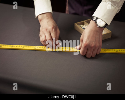 Tailor chalking measurements on table in traditional tailors shop Stock Photo