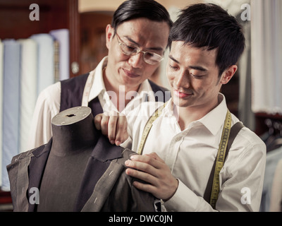 Father monitoring son in family tailoring business Stock Photo