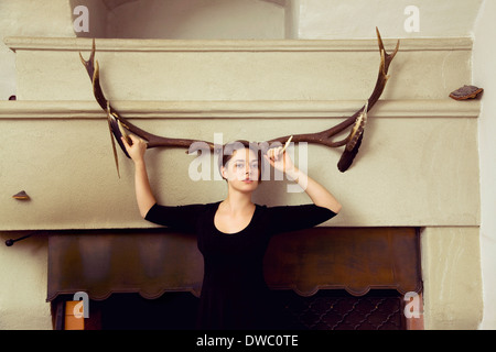Portrait of young woman standing in front of antlers Stock Photo