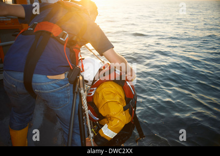 Lifeboat crew training and pulling up team member from sea Stock Photo