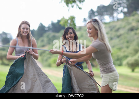 Three friends putting up tent whilst camping Stock Photo