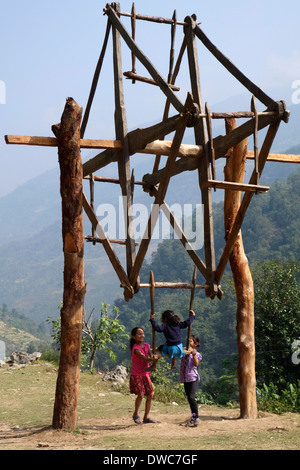 Children playing on a wooden ferris wheel in the Gorkha region of Nepal. Stock Photo