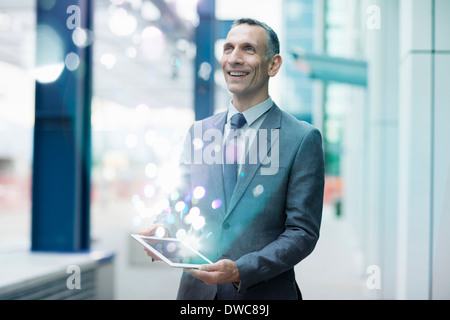 Businessman holding digital tablet with glowing lights coming out of it Stock Photo