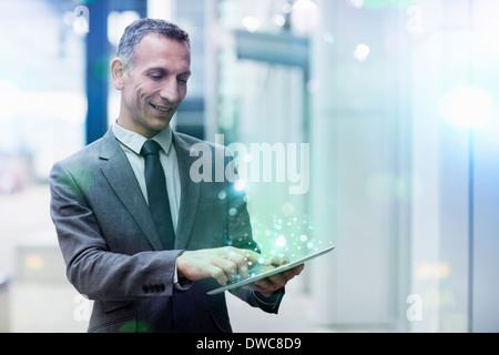 Businessman using digital tablet with glowing lights coming out of it Stock Photo
