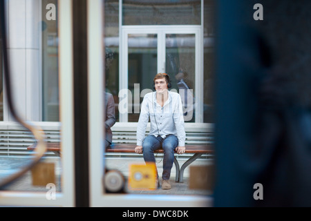 Young man sitting on train station bench Stock Photo