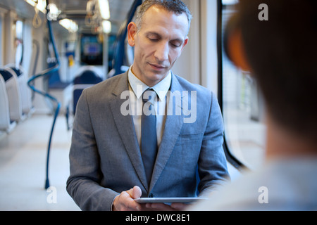 Businessman using digital tablet on train Stock Photo