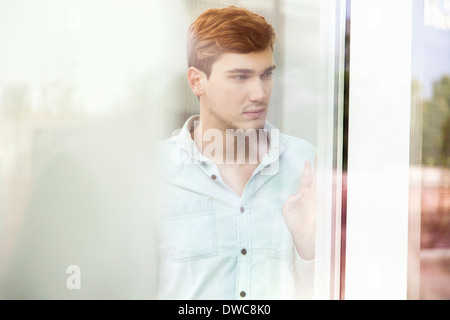 Unhappy young man looking out of window