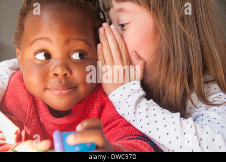 Close up of girl whispering to female toddler Stock Photo