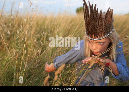 Girl hiding in long grass dressed up as a native american Stock Photo