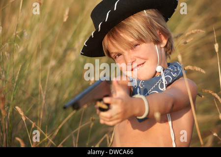 Portrait of boy in cowboy hat pointing toy gun Stock Photo