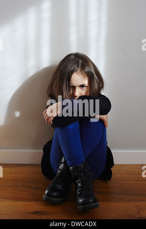 Young girl sitting, hugging knees, sad facial expression, on white ...