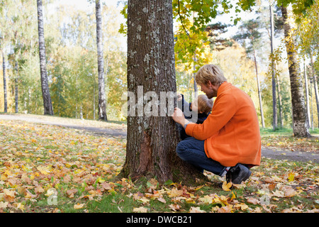Father and son playing at bottom of tree Stock Photo