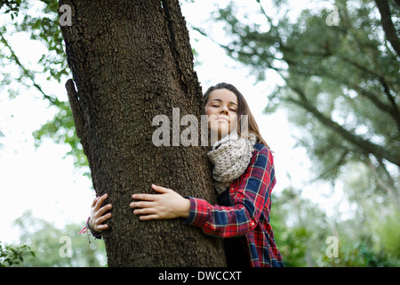 Teenage girl hugging tree in forest Stock Photo