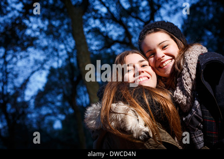 Sisters hugging in forest at dusk Stock Photo