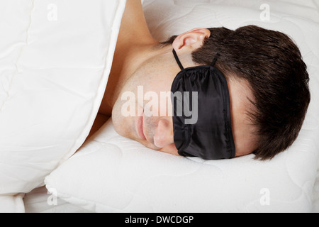 Man with Sleeping mask sleep lying in bed Stock Photo