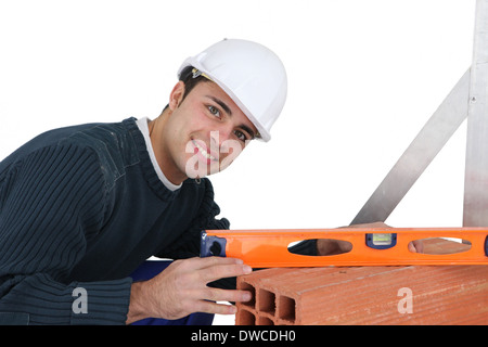 Young mason using spirit-level on aerated brick Stock Photo