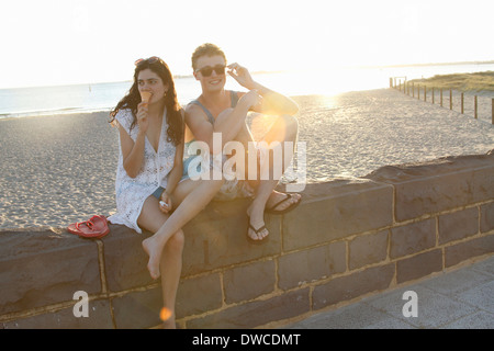 Young couple sitting on wall, Port Melbourne, Melbourne, Australia Stock Photo