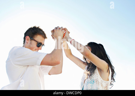 Young couple holding hands with arms raised Stock Photo
