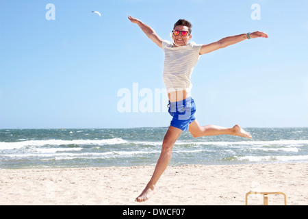 Young man leaping mid air on beach, Port Melbourne, Melbourne, Australia Stock Photo