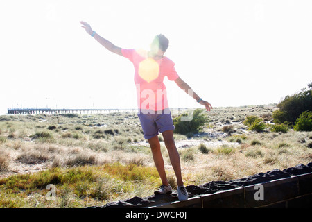 Young man balancing on wall near coast, Port Melbourne, Melbourne, Australia Stock Photo