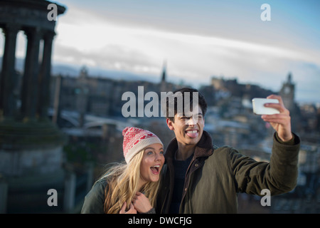 A young couple photograph themselves on Calton Hill with the background of the city of Edinburgh, capital of Scotland Stock Photo