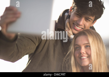 A young couple take self portrait photograph using digital tablet
