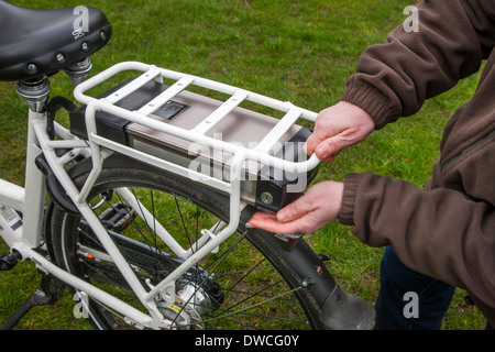 Man placing lithium-ion battery pack under rear carrier rack of pedelec / e-bike / electric bicycle Stock Photo