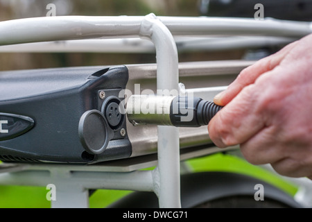 Man plugging cable in Li-ion battery pack to charge pedelec / e-bike / electric bicycle Stock Photo