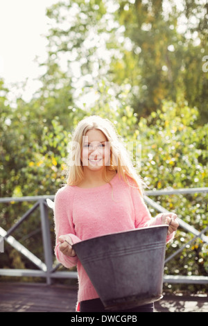 Portrait of smiling teenage girl carrying container in yard Stock Photo