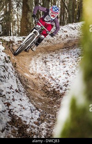 Young female mountain biker riding a forest dirt track Stock Photo