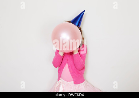 Girl holding pink balloon in front of face Stock Photo