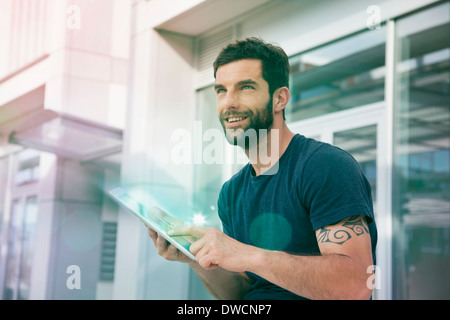Mid adult man using touchscreen on digital tablet with lights Stock Photo
