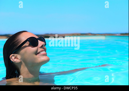 Mid adult woman wearing sunglasses relaxing in pool Stock Photo