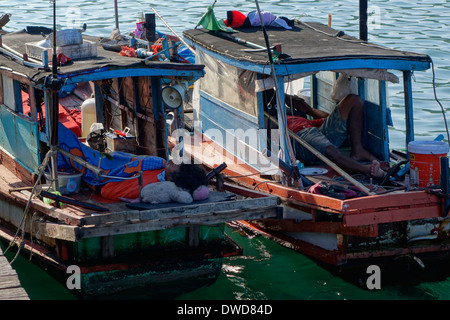 Fishermen sleeping on their boats along the pier in Ban Ao Yai, Koh Kood, Thailand. Stock Photo