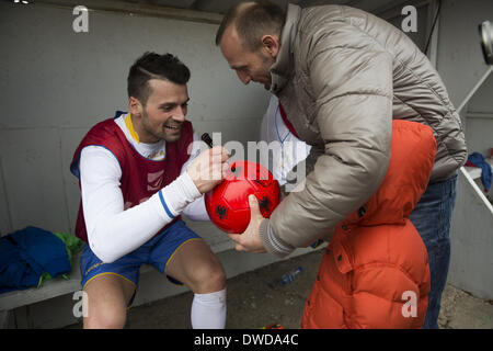 Pristina, Kosovo. 4th Mar, 2014. Kosovo National Team member Albert Bunjaku signs a ball for Joni Preniqi, 4, after practice at the KeK stadium on the Kastriot/Obilic district of Pristina. The will play their first FIFA sanctioned match, a friendly game against Haiti, on Wednesday March 5. PHOTO BY JODI HILTON/NURPHOTO © Jodi Hilton/NurPhoto/ZUMAPRESS.com/Alamy Live News Stock Photo