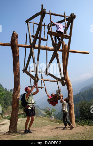 Trekker and children playing on a wooden ferris wheel in the Gorkha region of Nepal. Stock Photo