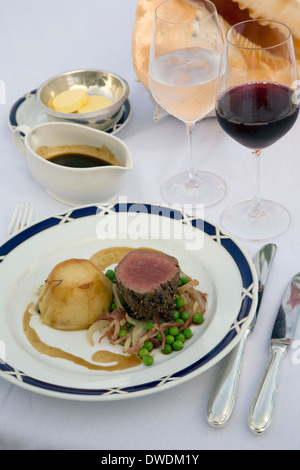 Peppered beef tenderloin with French-style peas and gratin potatoes at Orion's Delphinus Outdoor Cafe Stock Photo