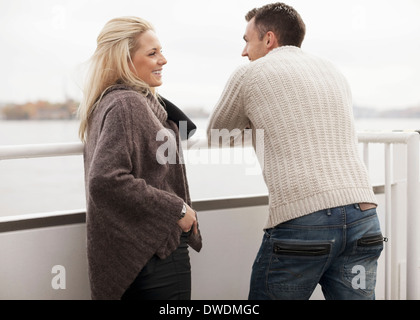 Young couple leaning on railing outdoors Stock Photo