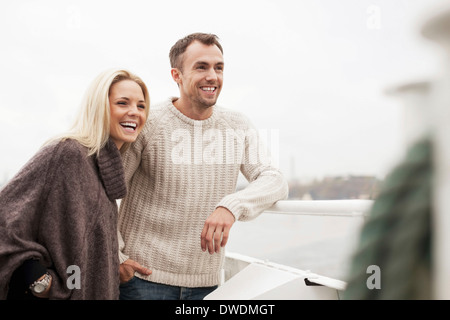 Happy young couple leaning on railing outdoors Stock Photo