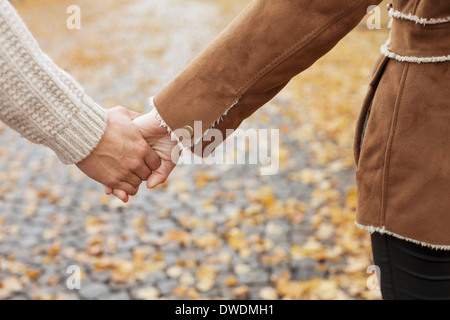 Midsection of couple holding hands during autumn Stock Photo