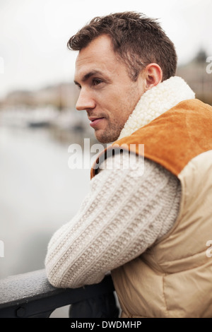 Thoughtful young man leaning on railing outdoors Stock Photo