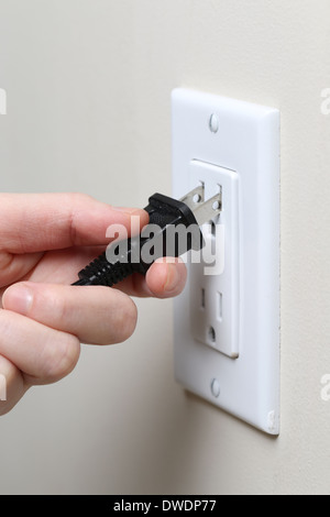 Hand inserting an electrical plug into a wall socket Stock Photo