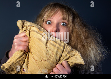 A frightened young woman watching a horror movie Stock Photo