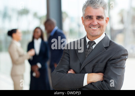 smiling senior business executive with arms folded in office Stock Photo