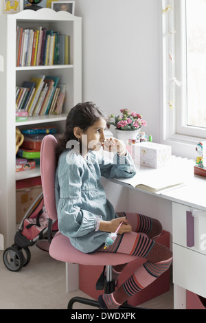 Thoughtful girl looking away while studying at home Stock Photo