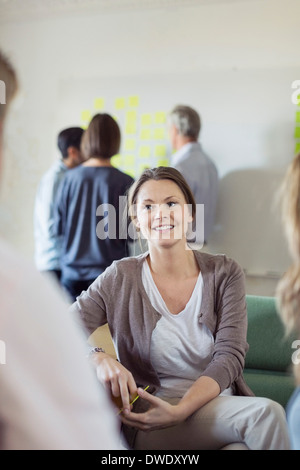 Smiling businesswoman with colleagues in board room Stock Photo