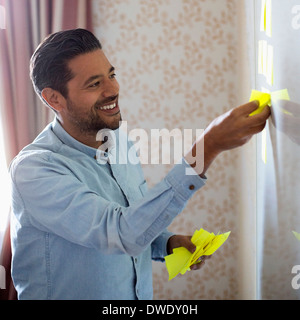 Smiling businessman removing memo notes from whiteboard in office Stock Photo