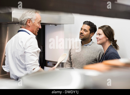 Chef talking to business people in commercial kitchen Stock Photo