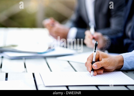 Cropped image of businessman writing on document at table Stock Photo