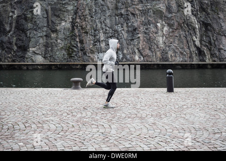 Man jogging on street against rock Stock Photo